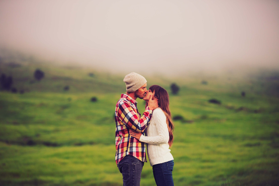a man and a woman are kissing in a field