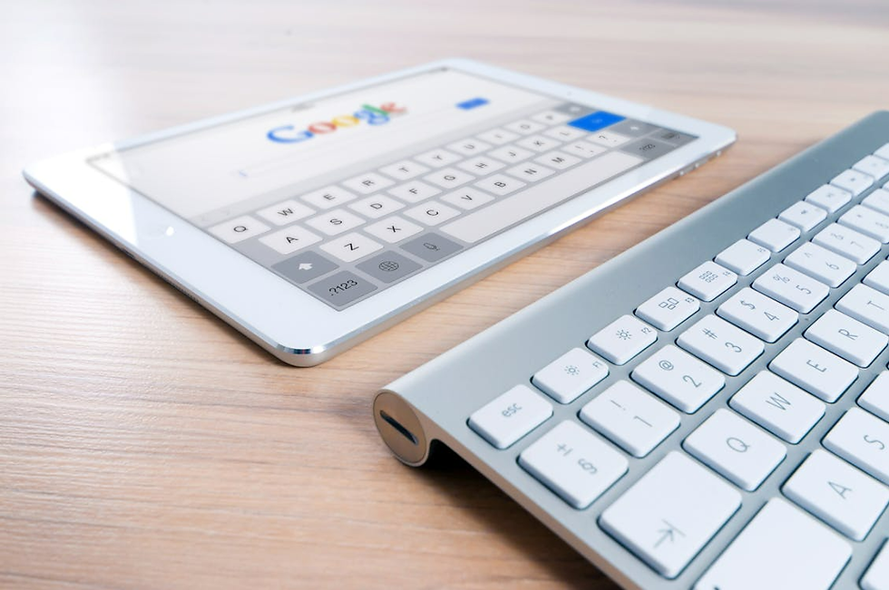 Tablet and keyboard on a wooden desk. The tablet displays a Google search page with a virtual keyboard. Bright, modern setting.