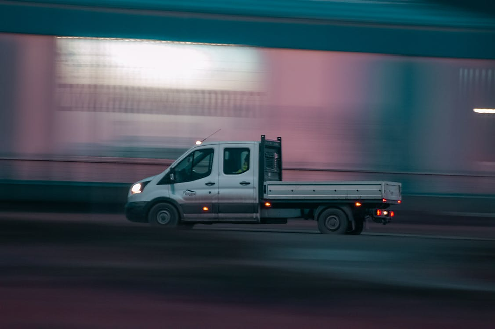 White flatbed truck speeds through a blurred tunnel at night, headlights on, with teal and pink streaks in the background.