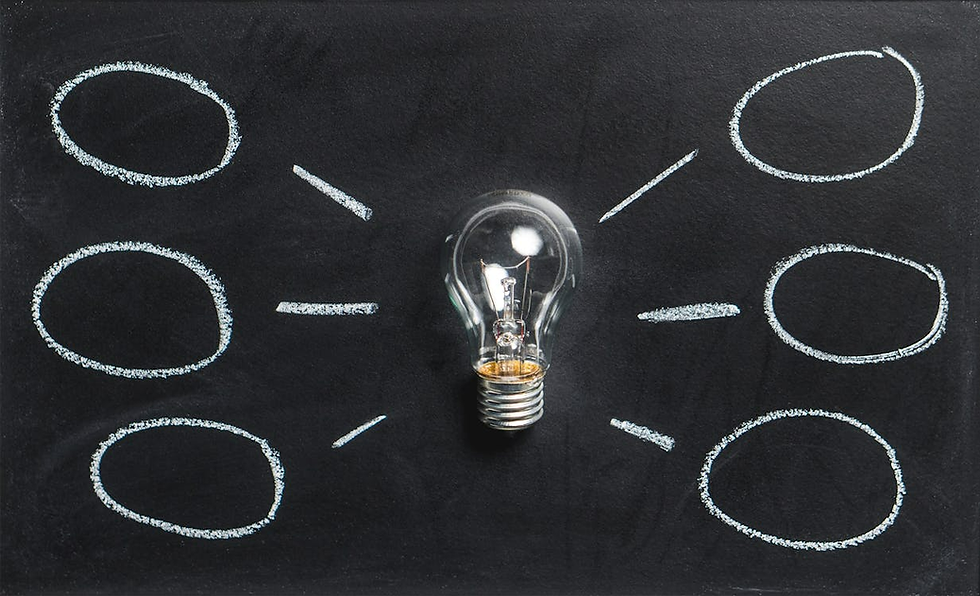 A light bulb on a black background with chalk circles and lines radiating outward, suggesting brainstorming or idea generation.