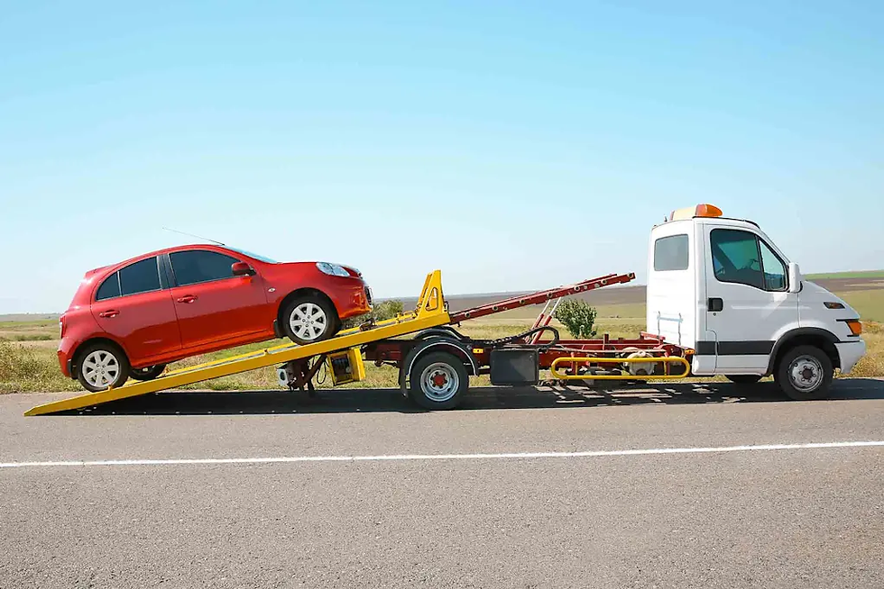 Red car being loaded onto a white tow truck on a rural road under a clear blue sky.