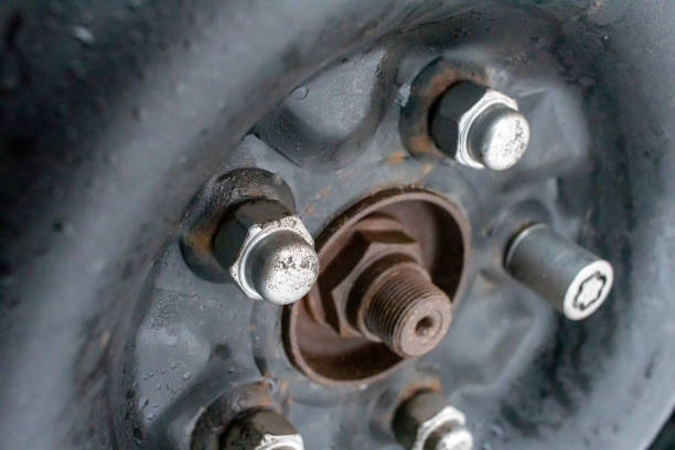 Close-up of a car wheel hub with lug nuts and a center axle stud on a dark rim.