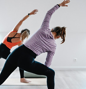 Twee personen die binnen yoga doen in een lichte ruimte