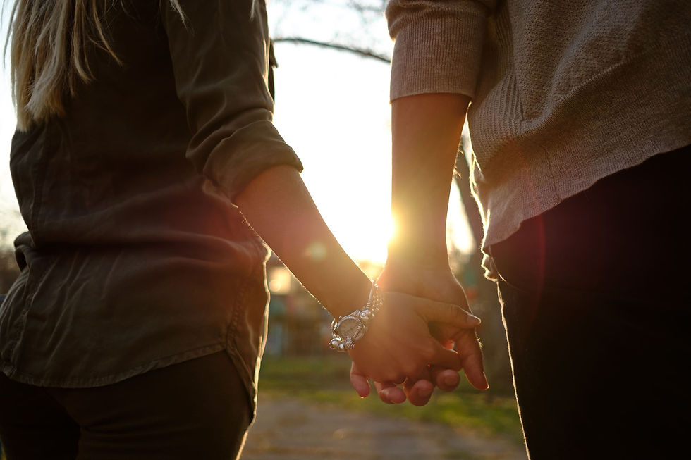 Duas pessoas caminhando de mãos dadas ao pôr do sol, simbolizando parceria, união e apoio mútuo.