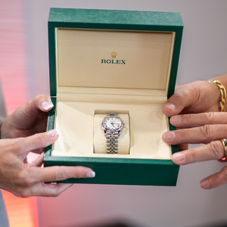 Two people holding a box with a new watch in it.
