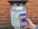 A QR code attached on a circular economy keg by a brick wall. There is a phone scanning the QR code and showing environmental data.