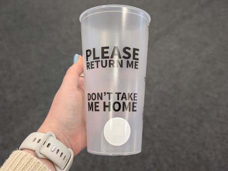 A reusable cup that says "Please Return Me" and "Don't Take Me Home" with a circular RFID tag attached to the bottom.