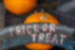 Pumpkin with a trick or treat sign hanging from it.