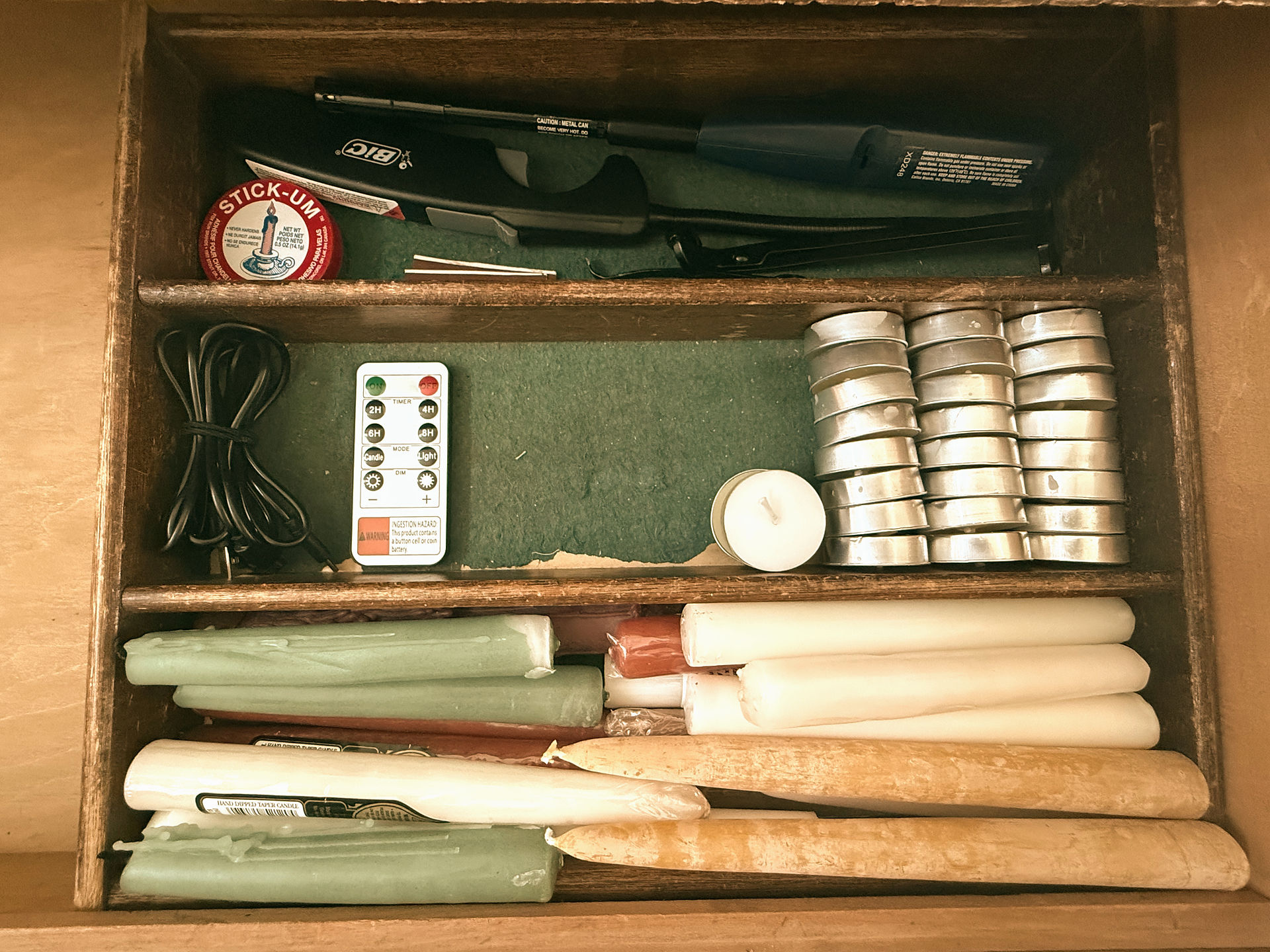Open drawer showing taper candles and lighters