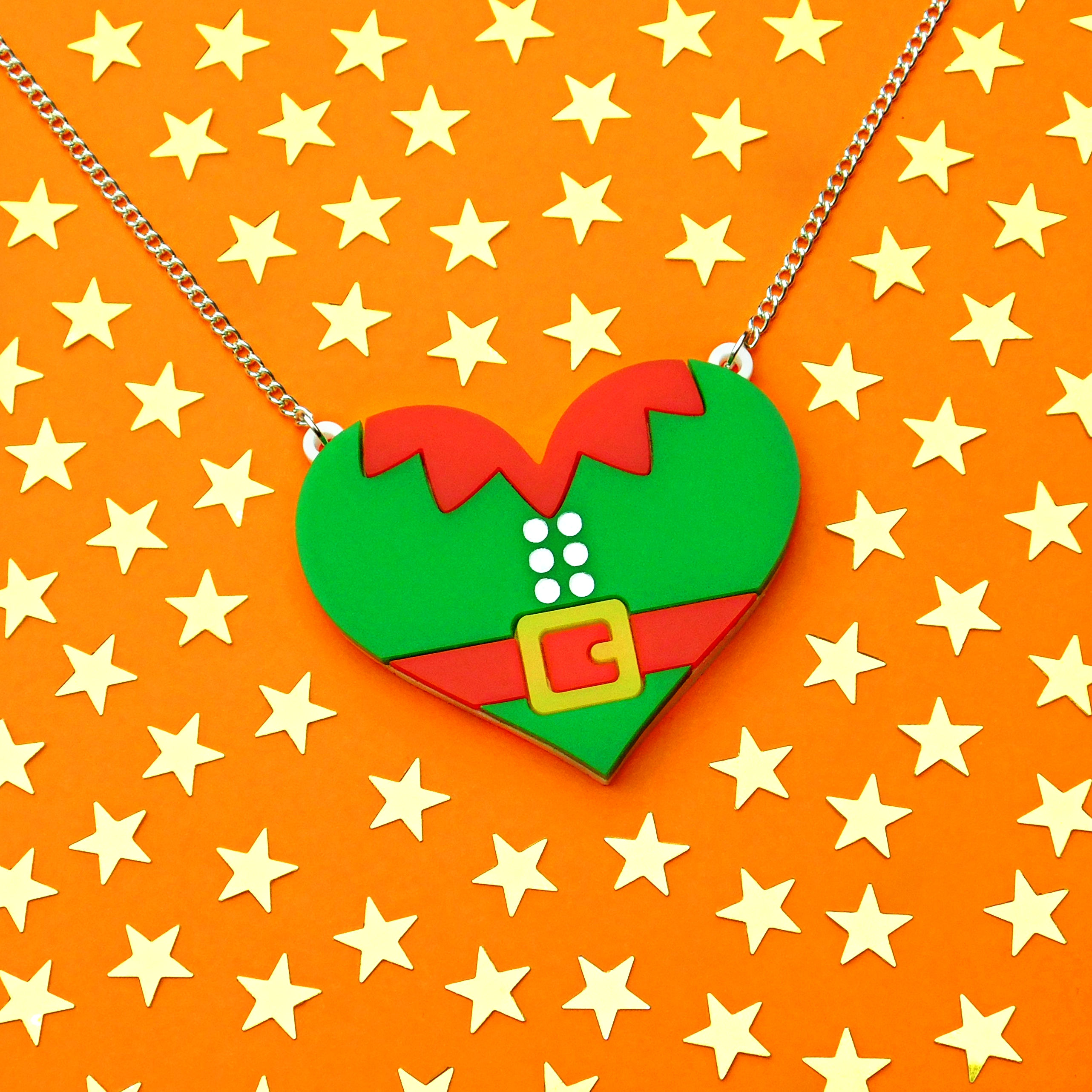 Head Elf heart necklace displayed on an orange background and surrounded by gold stars