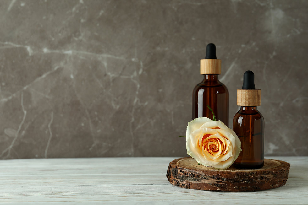 bottles-with-rose-essential-oil-and-rose-on-white-wooden-table.jpeg
