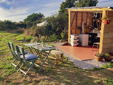 Rustic outdoor kitchen and seating at Foxglove Field boutique camping in Cornwall