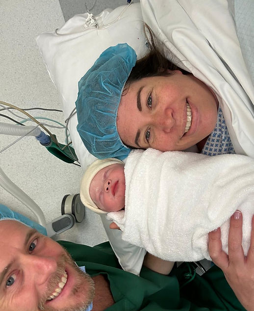 Mum holding her newborn baby next to her face with dad next to them