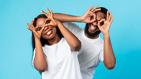 Having Fun. Portrait of joyful black couple smiling, looking at the camera through fingers