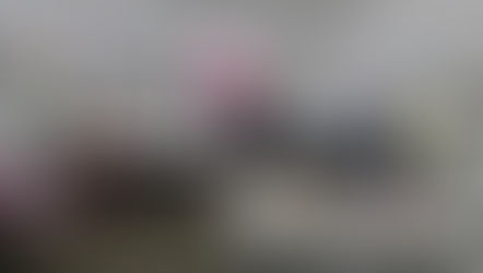 Fiber art students working at tables during a creative workshop, surrounded by colorful fabrics, paints, threads, and materials.