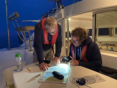 A student and skipper looking at charts during a night sail