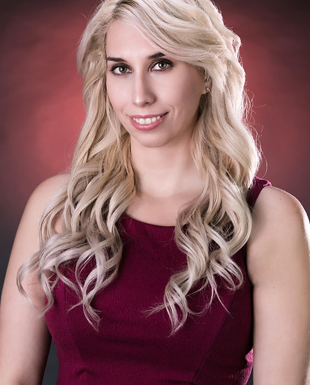 Portrait of he late Chrissy Adams - founder and owner of Breast La Vie. She has long blonde wavy hair and is wearing a read tank top with a red backdrop.