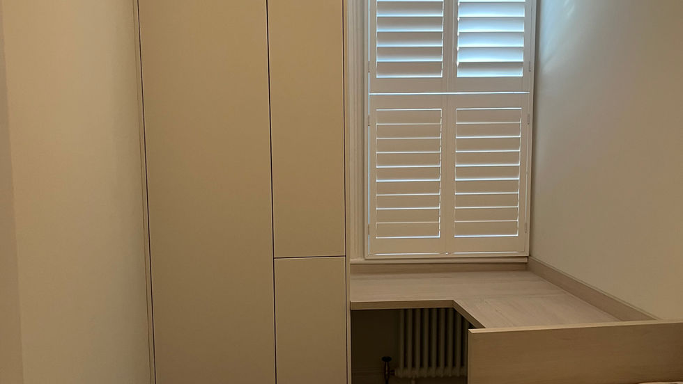 a tall built in white cupboard with a desk and day bed