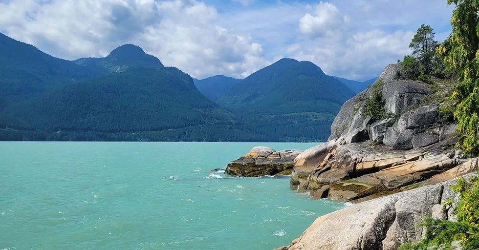 Bright blue water with mountains in the background. Can make out a rocky coastline to the right.