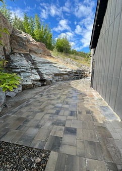 side of house walkway with pavers and gravel and rock-stacked retaining wall