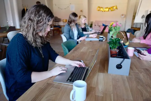 Coworking en una mesa de madera con diversos compañeros trabajando juntos