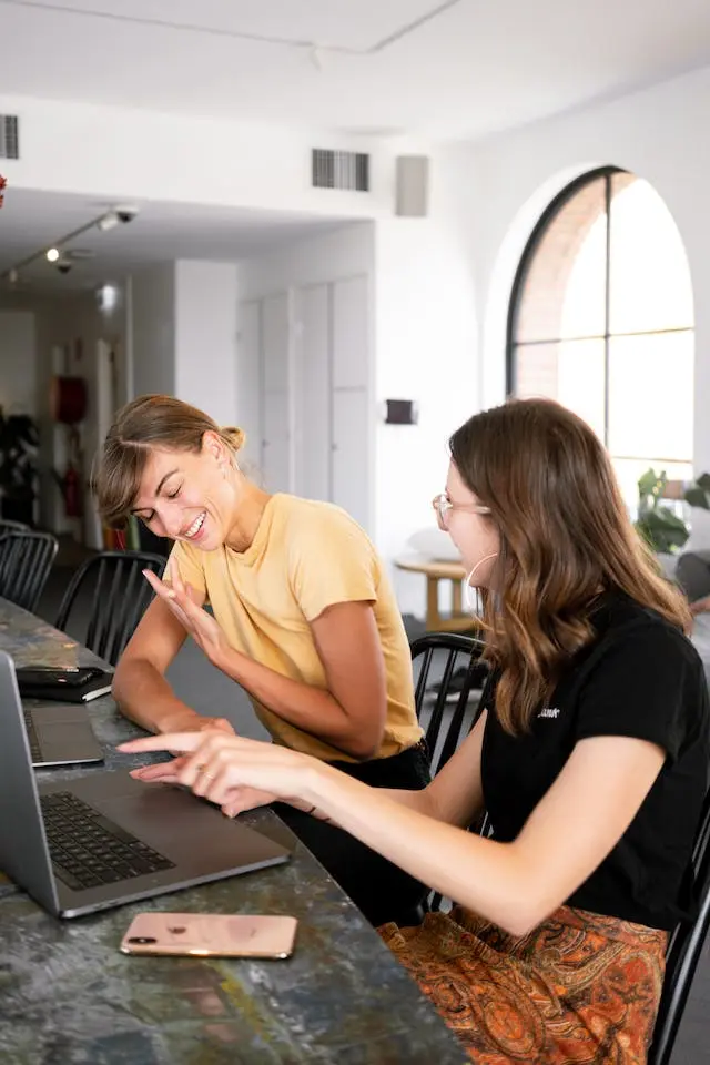 Dos compañeras en un coworking trabajando y riendose
