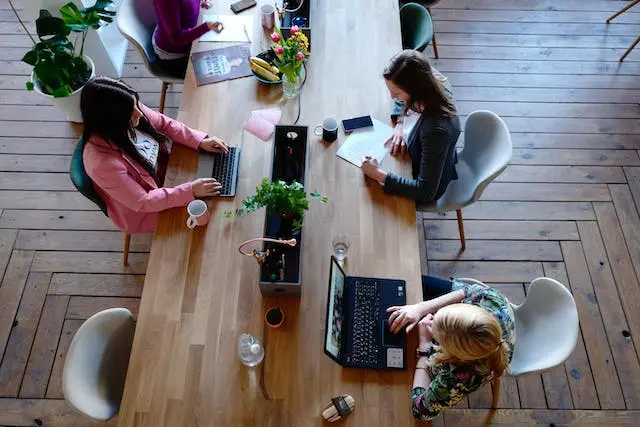 Mesa de coworking en valencia con 3 personas trabajando