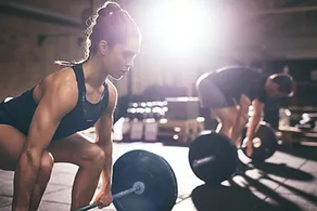 A woman and a man standing on a stage performing a dead lift.