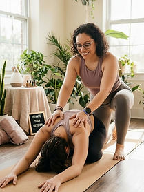 Image of Jo offering hands on assistance for student in childs pose