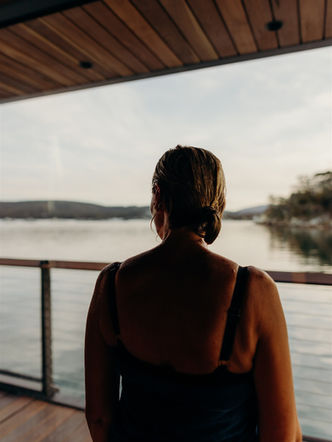 Guest relaxing inside KUUMA sauna and looking out over the water.