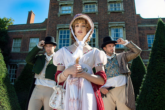 Handsome male couple and beautiful woman dressed in vintage clothing standing outside of s