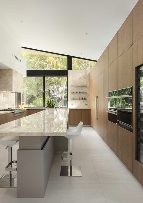 Pedini Arke kitchen with light grey matte lacquer uppers, oak veneer wall, and quartzite waterfall island with bar seating in a Coconut Grove Miami residence