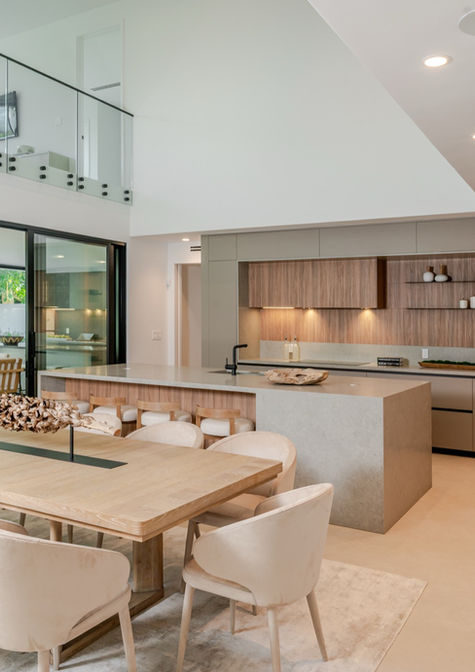 Pedini Moka kitchen and dining space in greige matte lacquer with warm wood-texture fronts, stone waterfall island, and double-height glazing in a Coconut Grove Miami residence