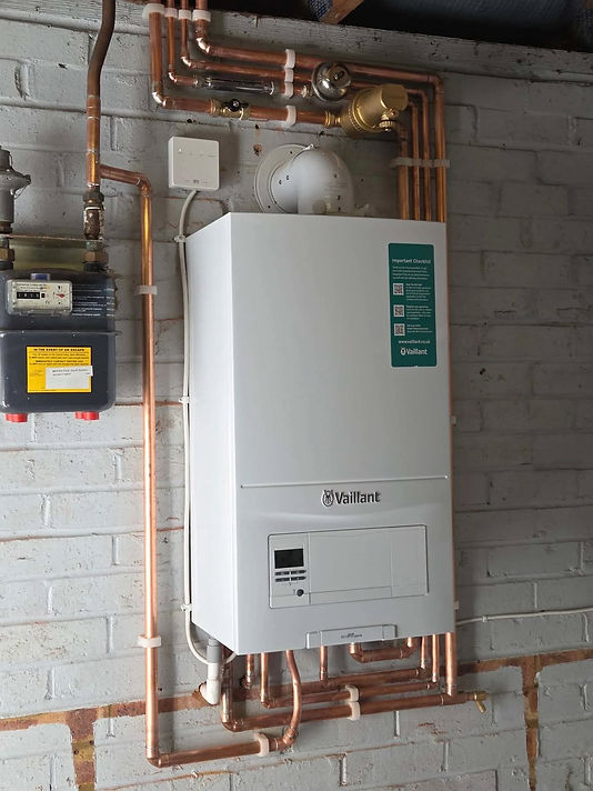 Wall-mounted white boiler with a control panel, installed on a light grey brick wall