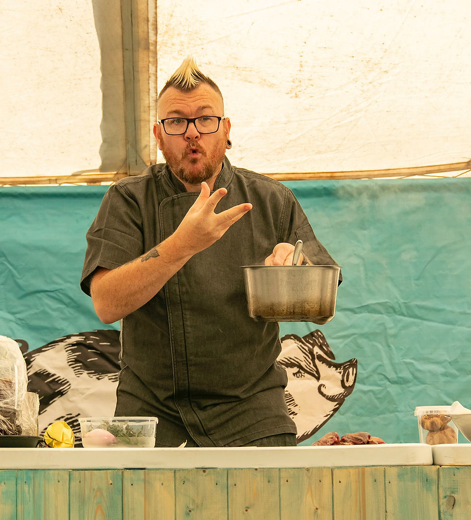 Punk Chef using sign language while holding a cooking pot