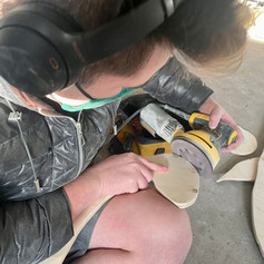 Artist, Aiden Lee sanding and shaping peices of wood.
