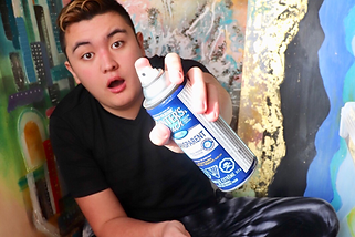 Artist Aiden Lee holding a spray paint can to the camera