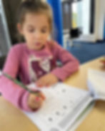 Young girl working on math activity sheets at a desk.