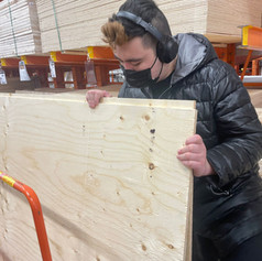 Artist, Aiden Lee selecting peices of plywood at a lumber store.