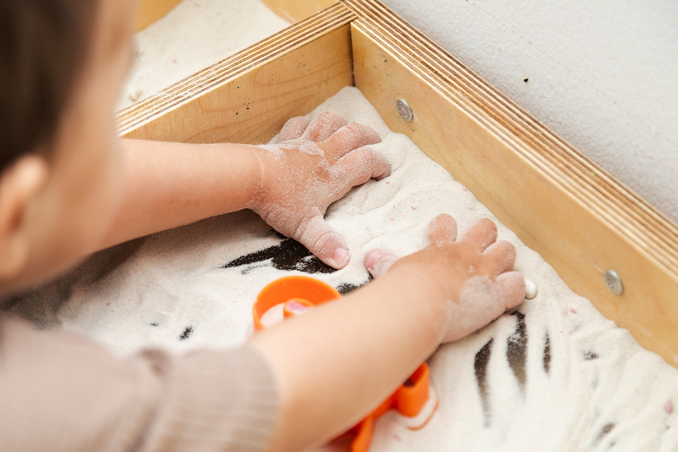 Toddler playing in a box of sand