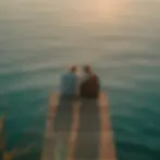 A man and woman sitting at the end of a pier