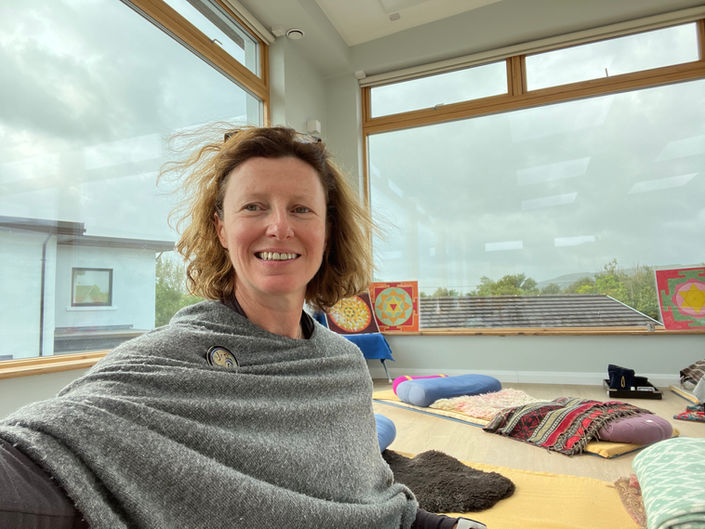 Woman smiling in yoga studio, overlooking cloudy day, Fiona Marshall Yoga.
