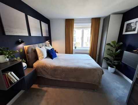 Trendy navy bedroom with ochre curtains