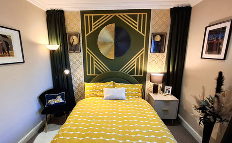 Art deco bedroom with geometric wall art, yellow bedding and olive green accessories