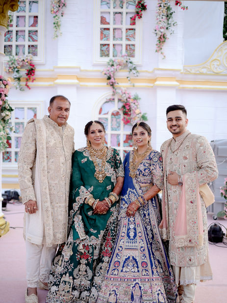 In a beautiful family moment, Dhruvi’s father stands on the right, exuding elegance in a white Sherwani with intricate gold embroidery. Beside him, Dhruvi’s brother (@p_jvn) wears a sophisticated ivory Sherwani, showcasing exquisite craftsmanship. At the center, Dhruvi’s Bhabhi (@_patel08) dazzles in a striking blue lehenga with intricate designs, while Dhruvi’s mother shines in a vibrant green lehenga with detailed hand embroidery. Together, they create a mesmerizing tableau of love, tradition, and Kolkata artistry.