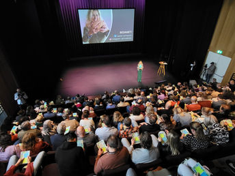 Saskia Verhaeren geeft een interactieve sprekerssessie voor een groot publiek in een theater. Congres.