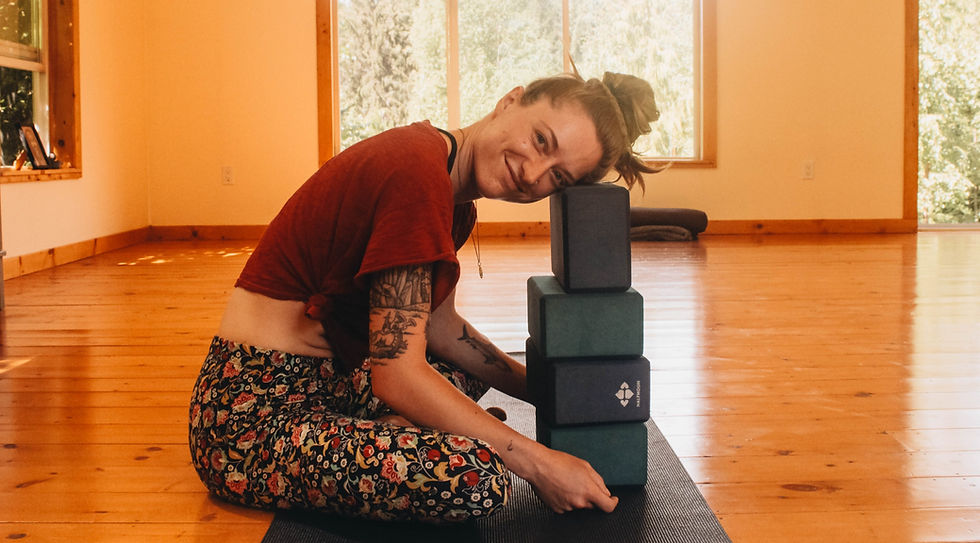 a woman smiling resting head on yoga blocks. Yoga as a science of consciousness