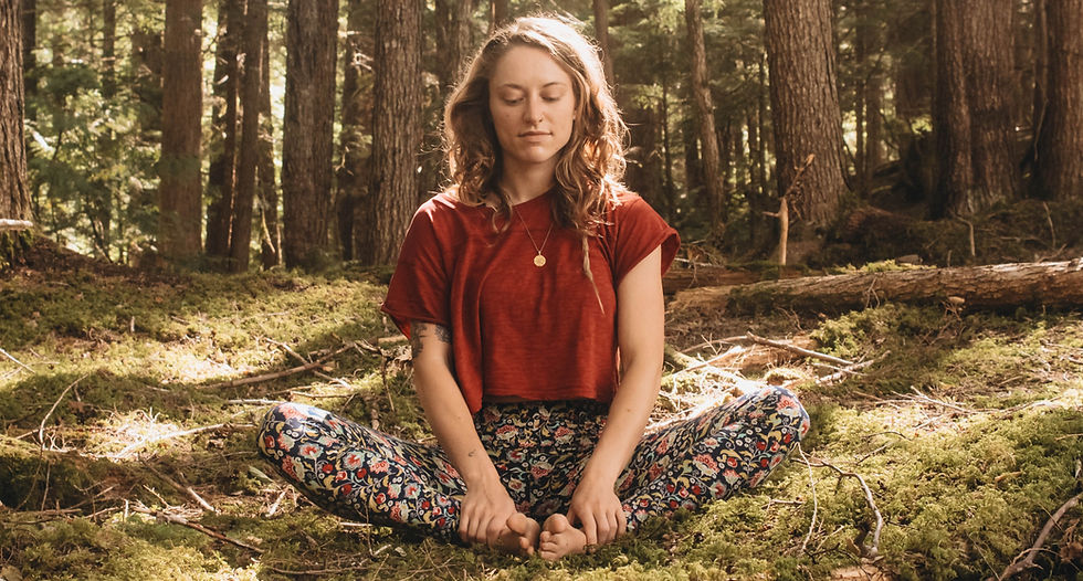 a woman sat in butterfly pose in a forest. Yoga as a science of consciousness