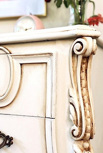 Close up of ornate antique nightstand refinished and painted in white chalk paint with a dark wax antiquing technique.