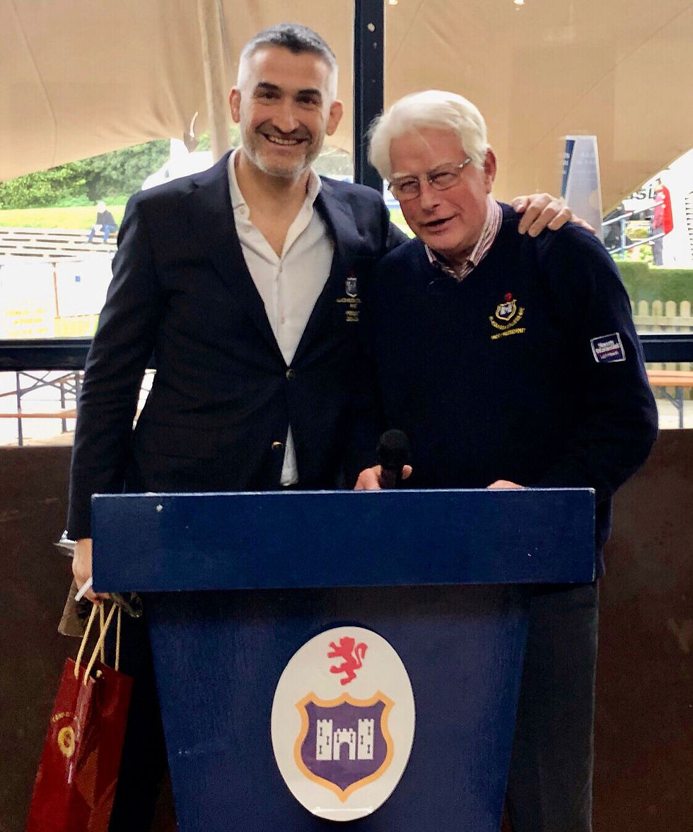 Two men in Blackrock College RFC navy blazers standing arm in arm behind a Blackrock RFC podium.
